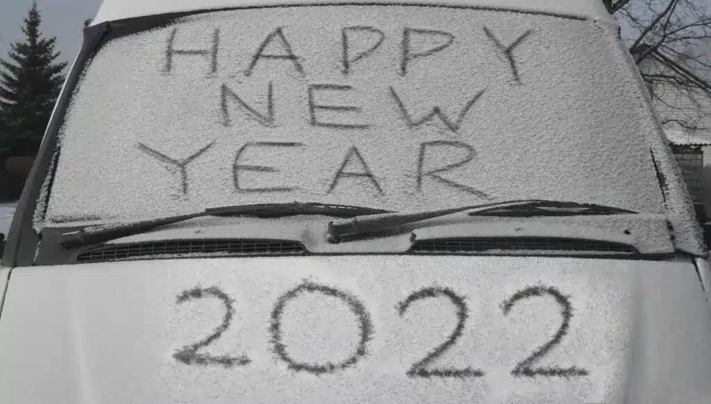 A snow-covered car with "Happy New Year" written on its windshield, symbolizing winter festivities and new beginnings.