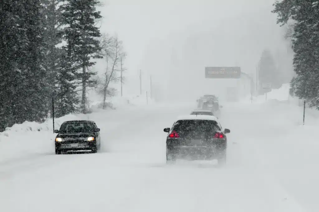 A vehicle drives along a snow-covered road