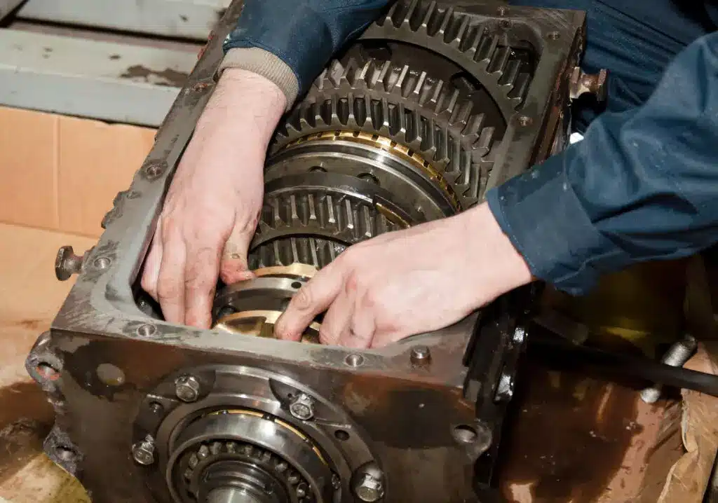 A man is focused on repairing a large gear box, showcasing his expertise in mechanical work