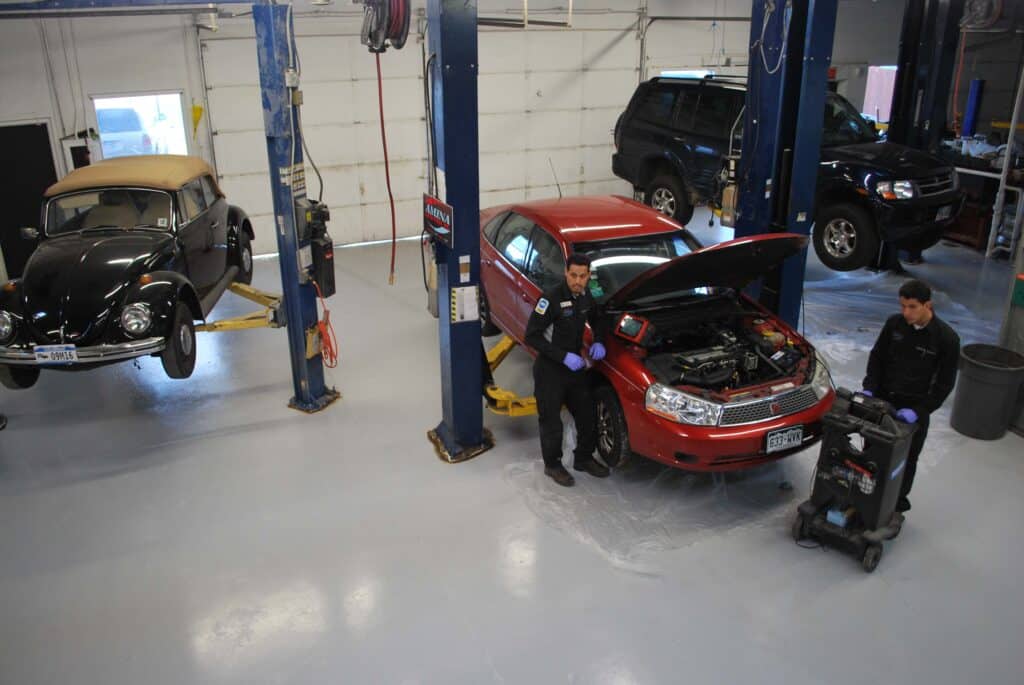 In the Express Auto Repair garage, two men collaborate on fixing a car, surrounded by tools and automotive parts.