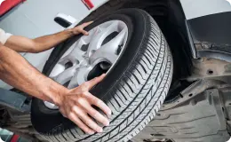 A person attaching a tire to a vehicle