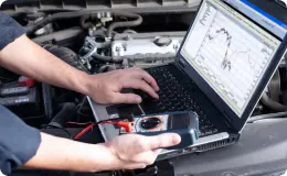 a mechanic on a laptop performing vehicle diagnostics