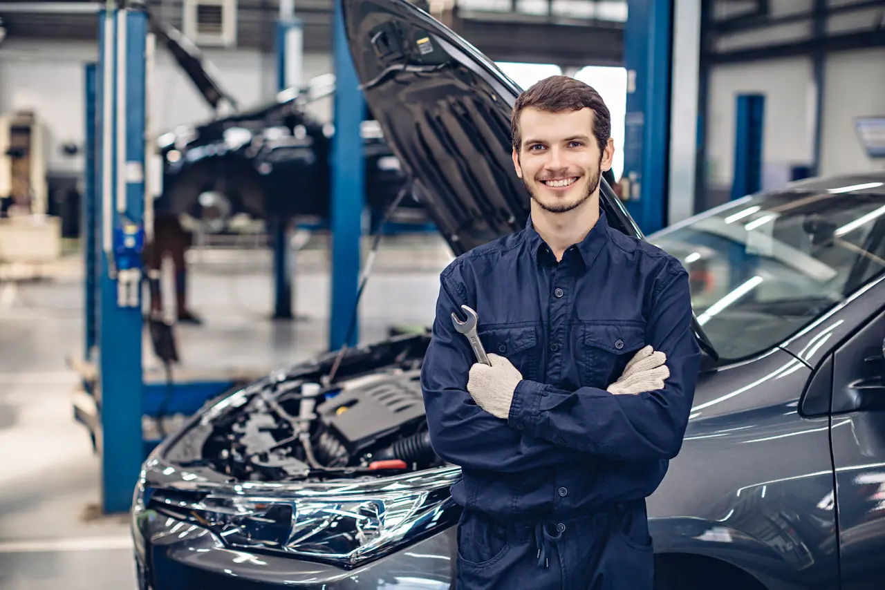 A happy man stands in front of a car, exuding positivity and a sense of accomplishment.