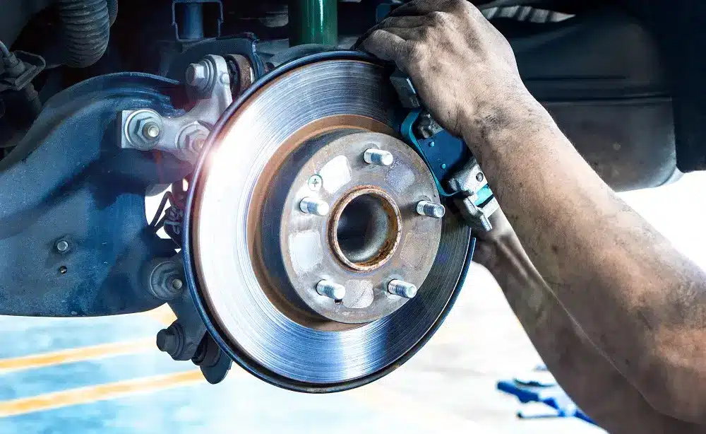 A man inspects and works on a brake disc, focusing on precision and detail in his mechanical task.