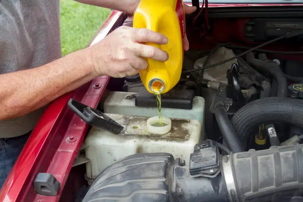 A man carefully pours oil into a car's engine, ensuring proper maintenance for optimal performance.