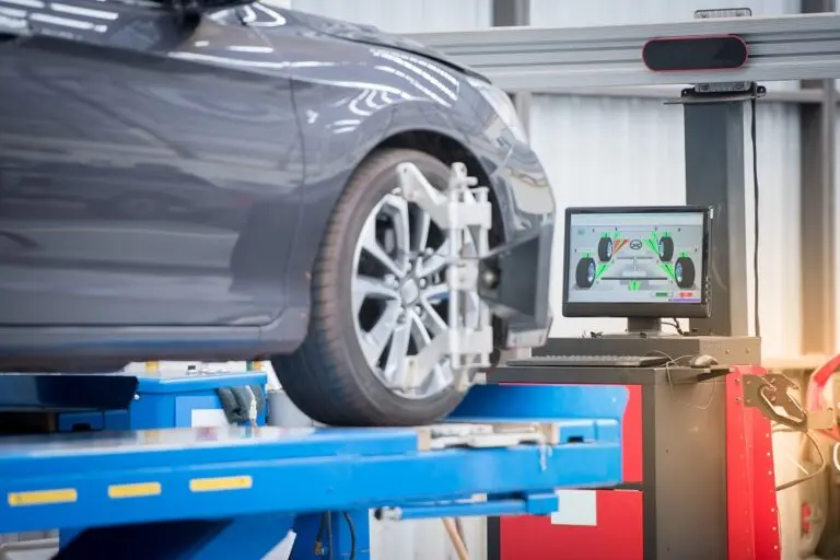 A car elevated on a lift inside a well-equipped garage, showcasing automotive maintenance and repair work.