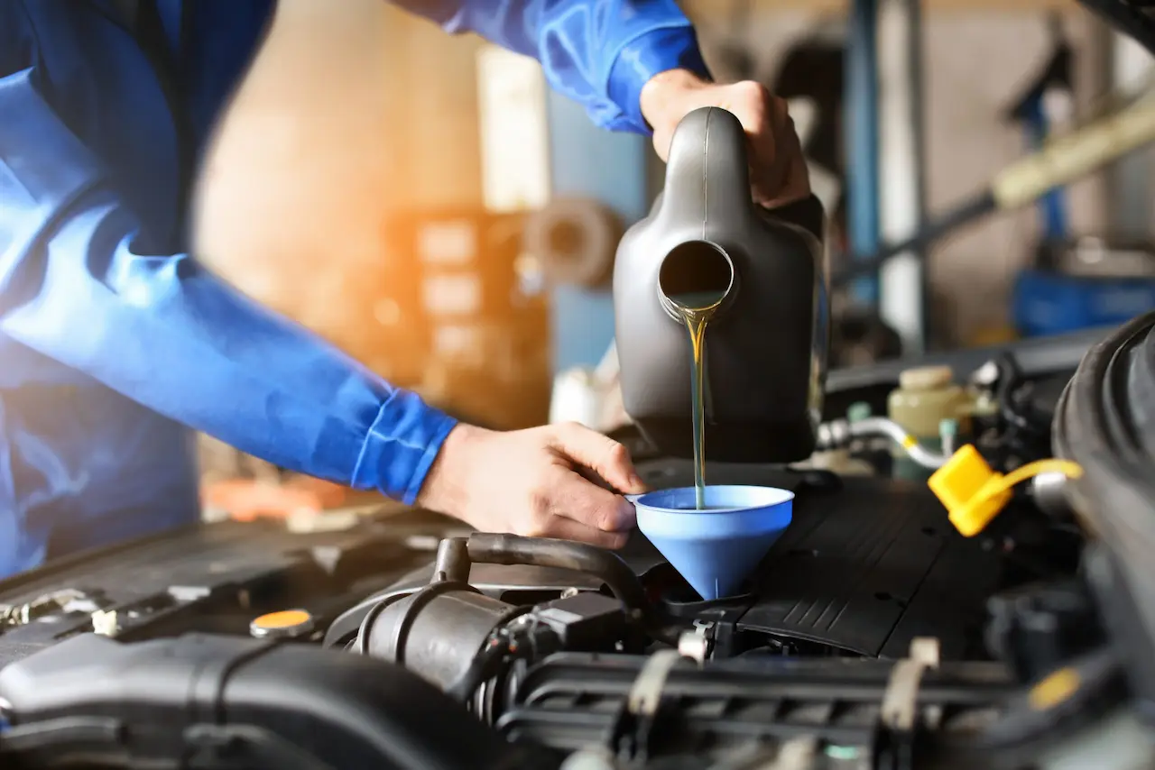 A man pours oil into a car engine, demonstrating essential upkeep for a smoothly running vehicle.