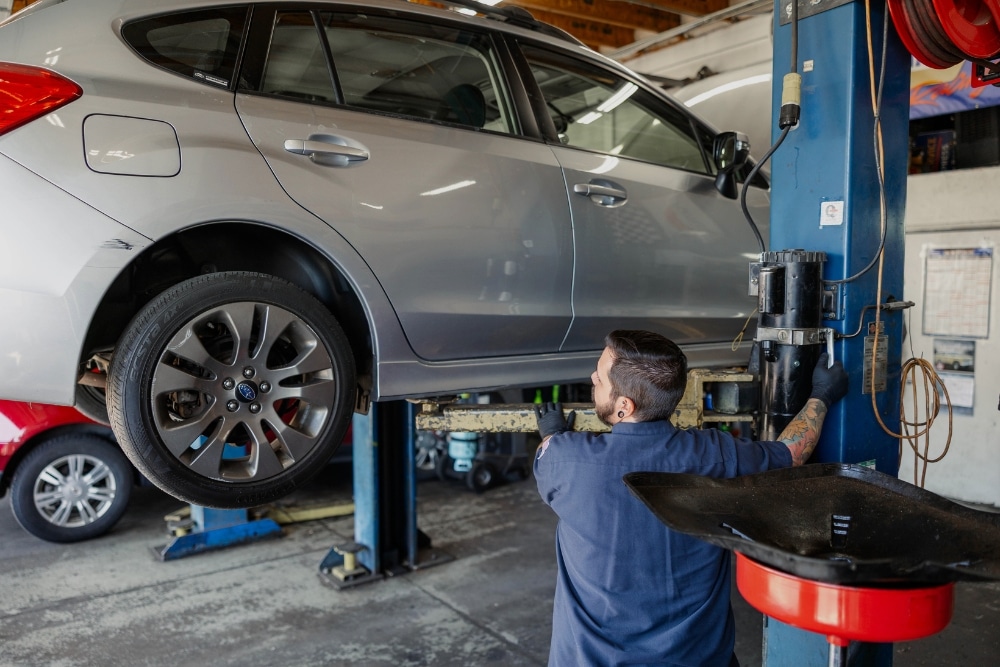 Auto Repair In Colorado Springs, CO At Express Auto Repair. Car lift with mechanic working in an auto repair shop.