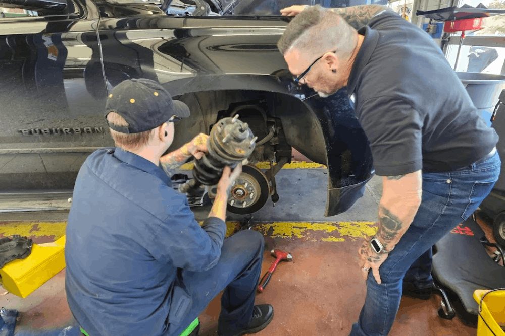 Steering and suspension repair in Colorado Springs, CO at Express Auto Repair. Image of technicians replacing suspension components on SUV, highlighting improved handling, ride comfort, and vehicle safety.
