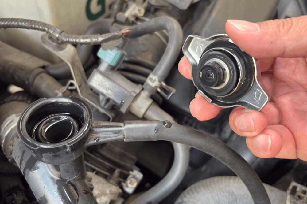 Radiator repair, auto repair in Colorado Springs, CO, at Express Auto Repair. Image of a technician removing a radiator cap during a cooling system inspection to diagnose leaks, regulate engine temperature, and help prevent overheating for safe, reliable performance.