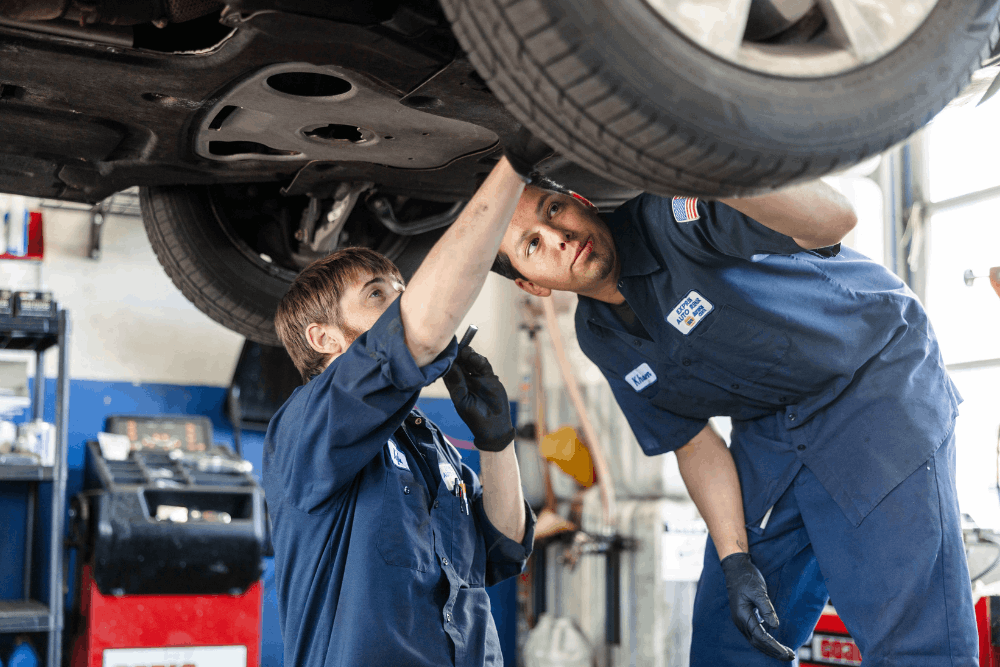 Fleet auto repair, auto repair in Colorado Springs, CO at Express Auto Repair. Image of two technicians examining components beneath a vehicle on a lift to support safe, reliable driving.