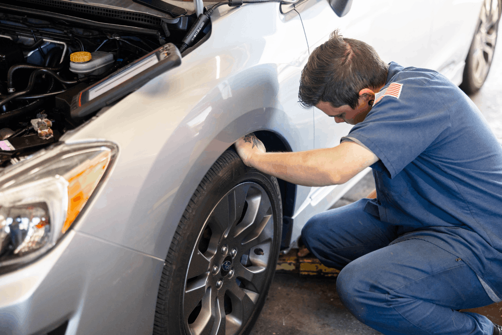 Car care, auto repair in Colorado Springs, CO at Express Auto Repair.Image of a technician inspecting the front wheel area of a vehicle to support safe handling and reliable maintenance.